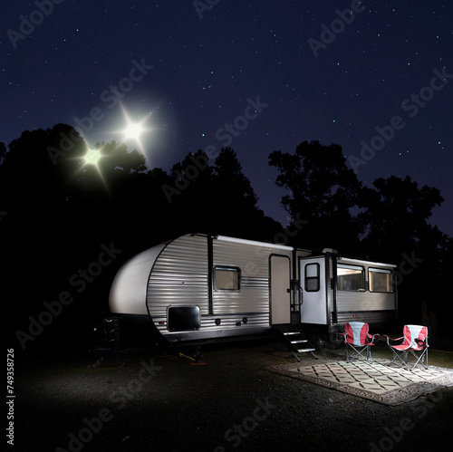 Two unidentified lights at night coming in over a camper trailer in a dark forest.