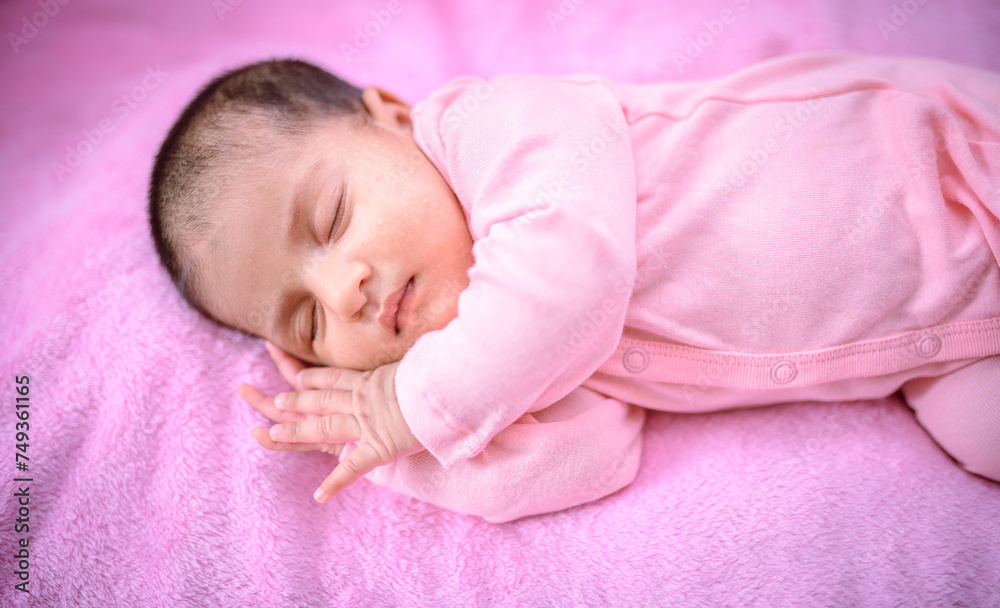 The newborn baby girl sleeps on pink bedding. The newborn baby girl sleeps on pink bedding.