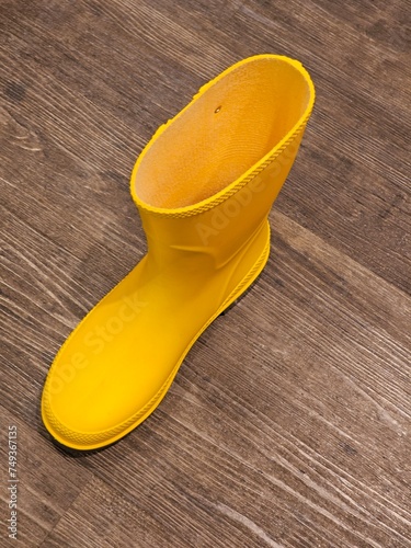yellow gum boot rest atop a rustic wooden floor, adding a pop of color to the natural surroundings.