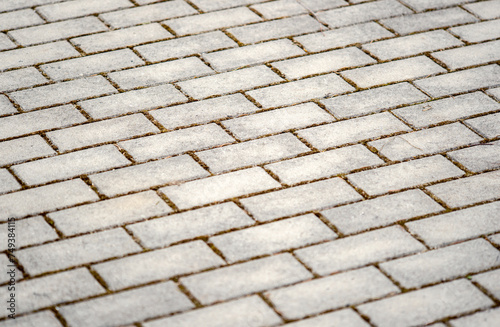 Detailed view of the pattern and texture of worn grey paving bricks laid out outdoors, simple minimal backdrop background texture, angle shot, no people. Rectangle paving bricks outside, shallow DOF