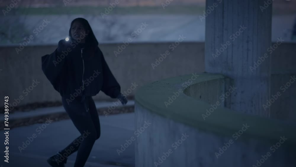 Fearful Young Woman Holding Flashlight Outside in Dark Night