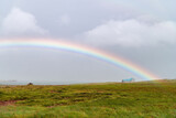 Panoramic view over some farmland in the north of Iceland with lone farm building against the backdrop of the Breiðafjörður (fjord) with dark clouds and rainsbow