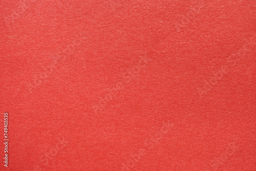 Close-up view of bright red textured paper, perfect for backgrounds or graphic design projects.
