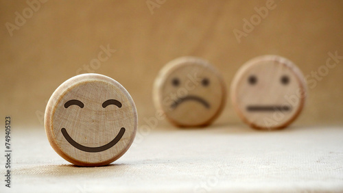 Wooden round with carved happy and angry faces, International Day of Happiness concept, customer reviews, emotional intelligence, emotional control balance, feedback rating, mental health assessment.