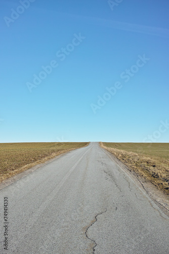 Blue sky, road trip and desert landscape for travel, holiday and natural scenery in countryside. Nature, horizon and street for journey, vacation or outdoor adventure with peace, relax and wilderness