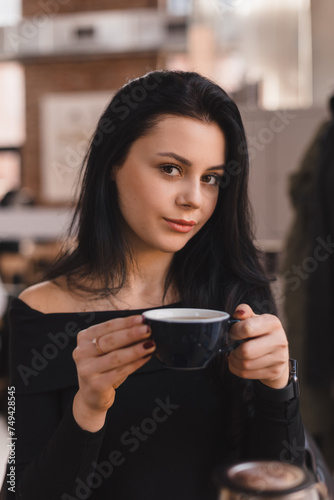 Thoughtful brunette teen woman drinking coffee in cafe, lifestyle, coffee, communication and local business, unaltered. Sensual woman look at camera.