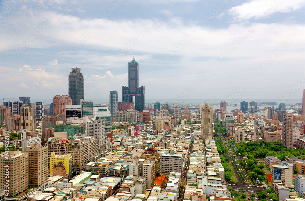 Obraz premium Cityscape of Kaohsiung Downtown, a vibrant seaport city in Southern Taiwan, with the landmark 85 Sky Tower standing out among modern buildings and ships parking in the harbor under cloudy sunny sky