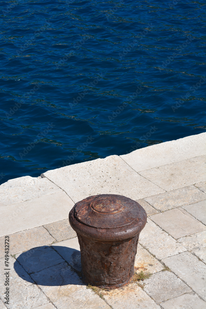 Rusted iron mooring post for boats on a stone pier Rusted iron mooring post for boats on a stone pier