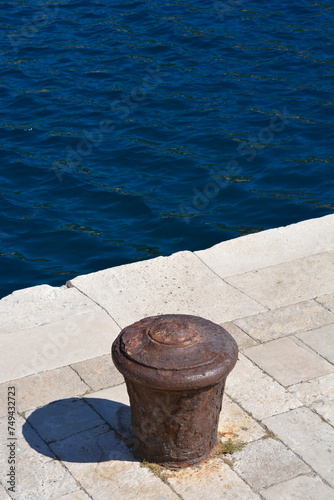 Rusted iron mooring post for boats on a stone pier