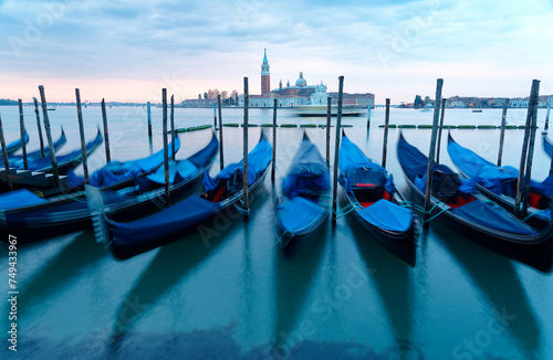 Early morning scenery of Venice with San Giorgio Maggiore Church in the background & gondolas parking on the Grand Canal in blue twilight, viewed from St Mark's Square in Venezia, Italy, Europe