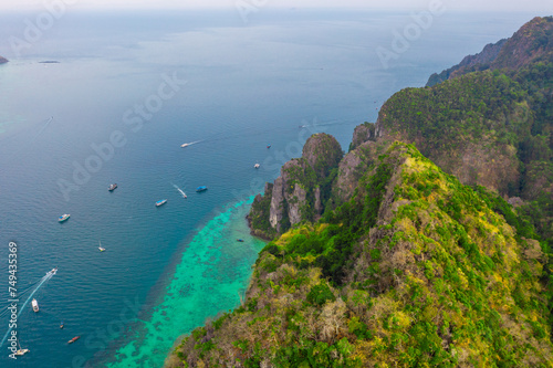Tropical group of islands rocks dense jungle wild animals untouched nature, blue lagoon and bay with coral reefs near the beach. Speed Boats ship tourists island vacation relaxation. Aerial top view