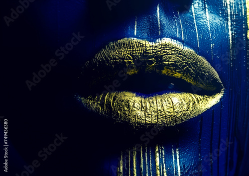 Contemporary abstract art. Juicy female lips in the center of the frame. Dark paint with liquid gold flows from the face. Close-up