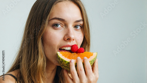 young woman being healthy eating a fruit on a clean background