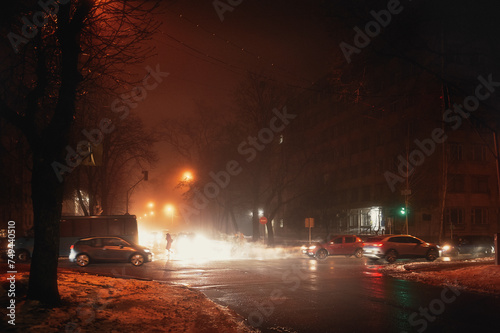 Street fog in the city at the intersection with cars in winter, red tinting