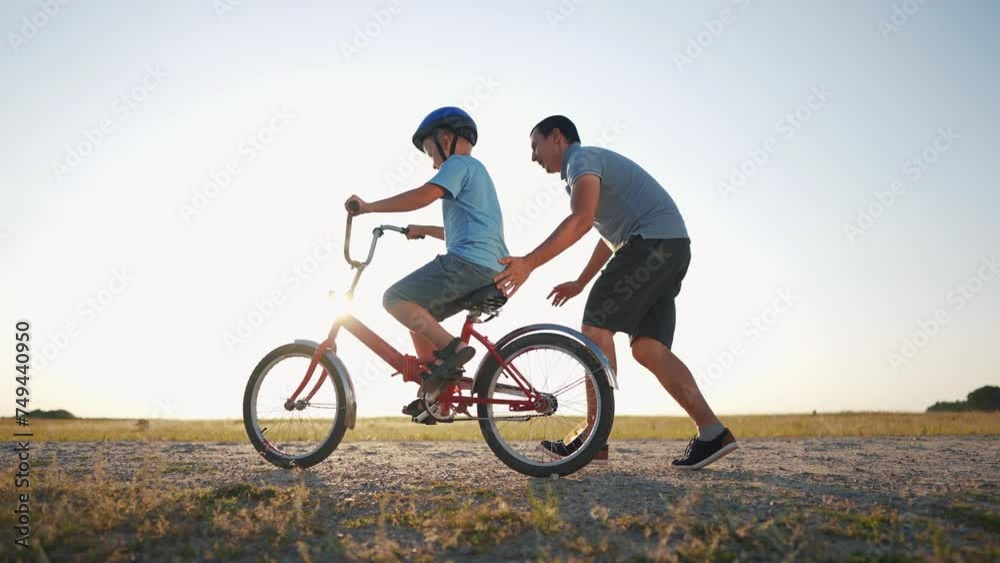 family play in the park. father teaching son to ride a bike. happy family kid dream concept. son learn to ride a bike silhouette. father supporting child son riding bike sunset summer in the park family play in the park. father teaching son to ride a bike. happy family kid dream concept. son learn to ride a bike silhouette. father supporting child son riding bike sunset summer in the park