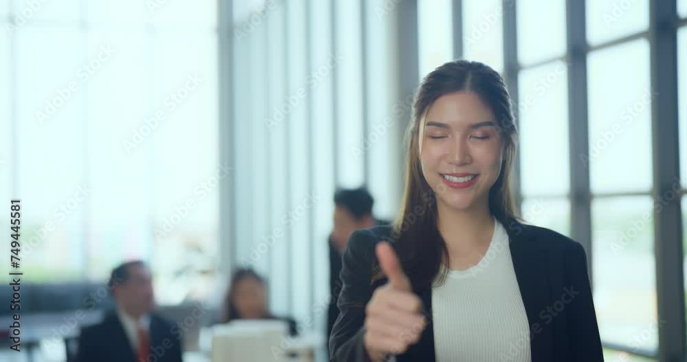 Smiling young female professional giving a thumbs up in a modern office setting, signaling success or agreement. Smiling young female professional giving a thumbs up in a modern office setting, signaling success or agreement.