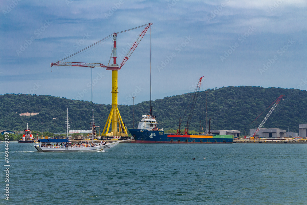 SANTOS, SP, BRAZIL - JANUARY 02, 2024: Ship UP RUBI, tug, schooner and a big crane seen from the Ponta da Praia.