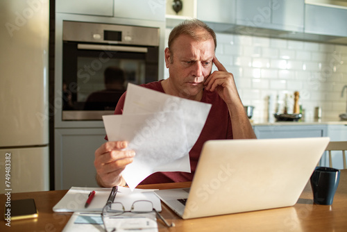 Stressed man going over bills at home