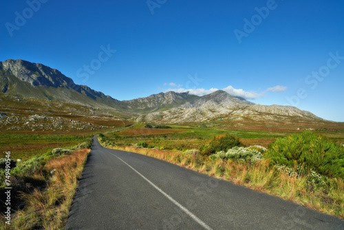Mountain, road trip and natural landscape with grass, holiday or green scenery in countryside. Nature, grass and highway for journey, vacation or outdoor adventure with blue sky, relax and tranquil