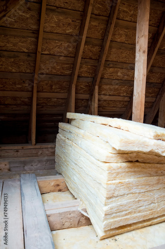 Insulating the roof of a house. Bales of fiberglass are laid out in the attic.
