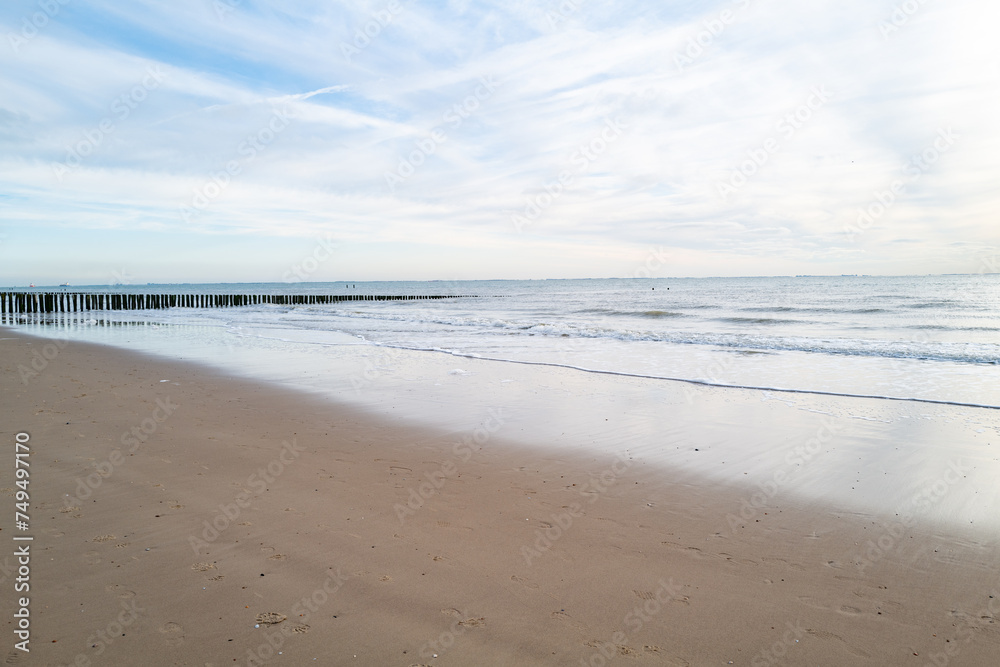 lonely beach with waves and sky in zeeland, the netherlands