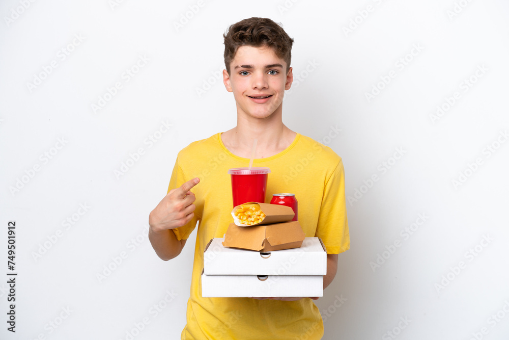 Teenager Russian man holding fast food isolated on white background pointing to the side to present a product Teenager Russian man holding fast food isolated on white background pointing to the side to present a product