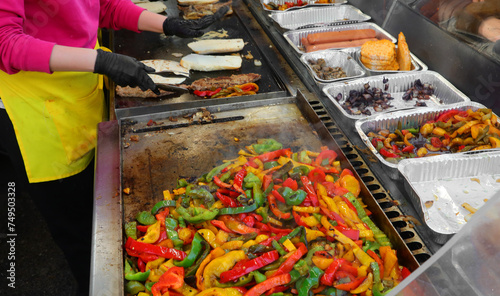 sizzling hot griddle on a street food truck counter is preparing mouth-watering sandwiches filled with rilled sausage and roasted peppers photo