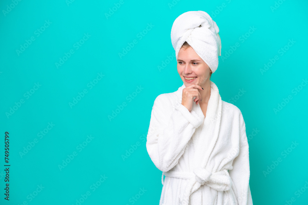 Young woman in a bathrobe isolated on blue background looking to the side Young woman in a bathrobe isolated on blue background looking to the side