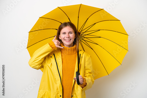 Young English woman with rainproof coat and umbrella isolated on white background making phone gesture. Call me back sign