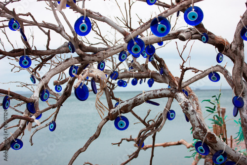 Evil eye beads on dry tree leaves. Evil eye bead decoration on a tree by the seaside. Close up traditional Turkish evil eye symbol.