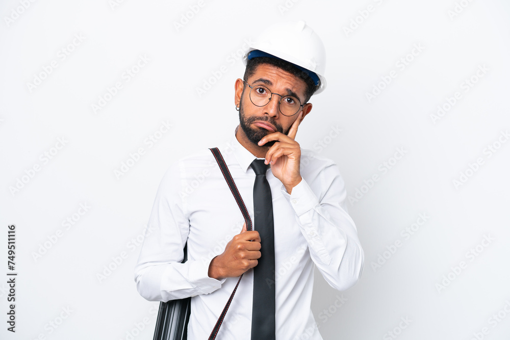 Young architect Brazilian man with helmet and holding blueprints isolated on white background thinking an idea Young architect Brazilian man with helmet and holding blueprints isolated on white background thinking an idea