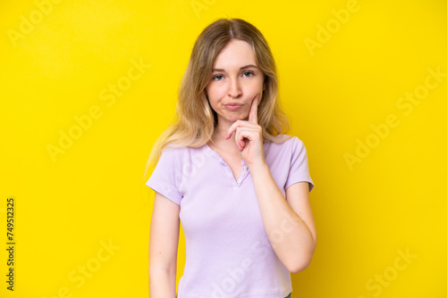 Blonde English young girl isolated on yellow background and thinking