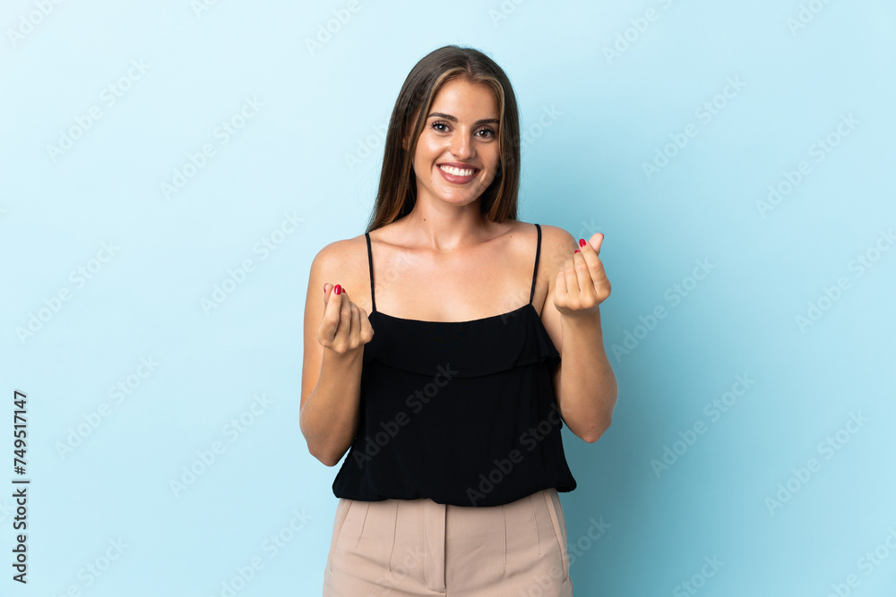 Young Uruguayan woman isolated on blue background making money gesture Young Uruguayan woman isolated on blue background making money gesture