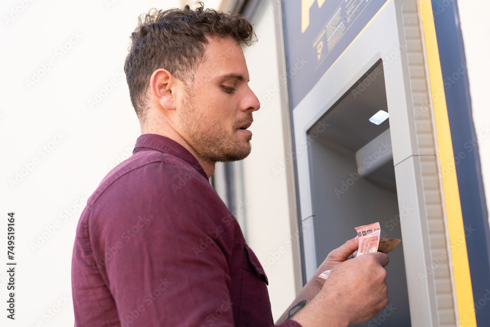 Young caucasian man at outdoors using an ATM