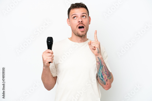 Young caucasian singer man picking up a microphone isolated on white background thinking an idea pointing the finger up