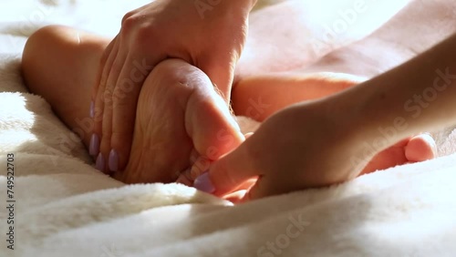 A girl gives a foot massage to a man at home in the bedroom on the bed, foot massage photo