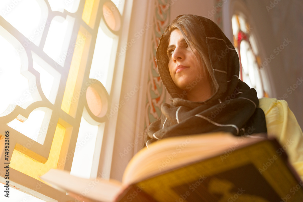 Young muslim woman reading Quran in the mosque. woman praying and reading quran in mosque during ramadan