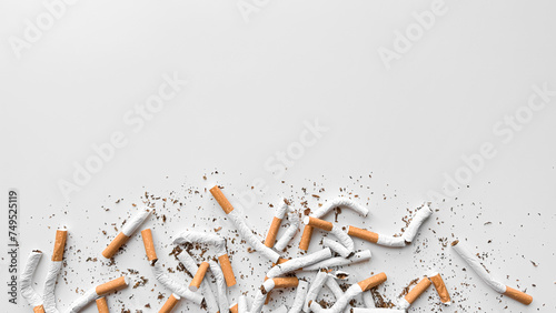 Discarded crushed broken cigarettes and scattered tobacco on white background, representing cessation and the end of smoking with copy space. No tobacco day.