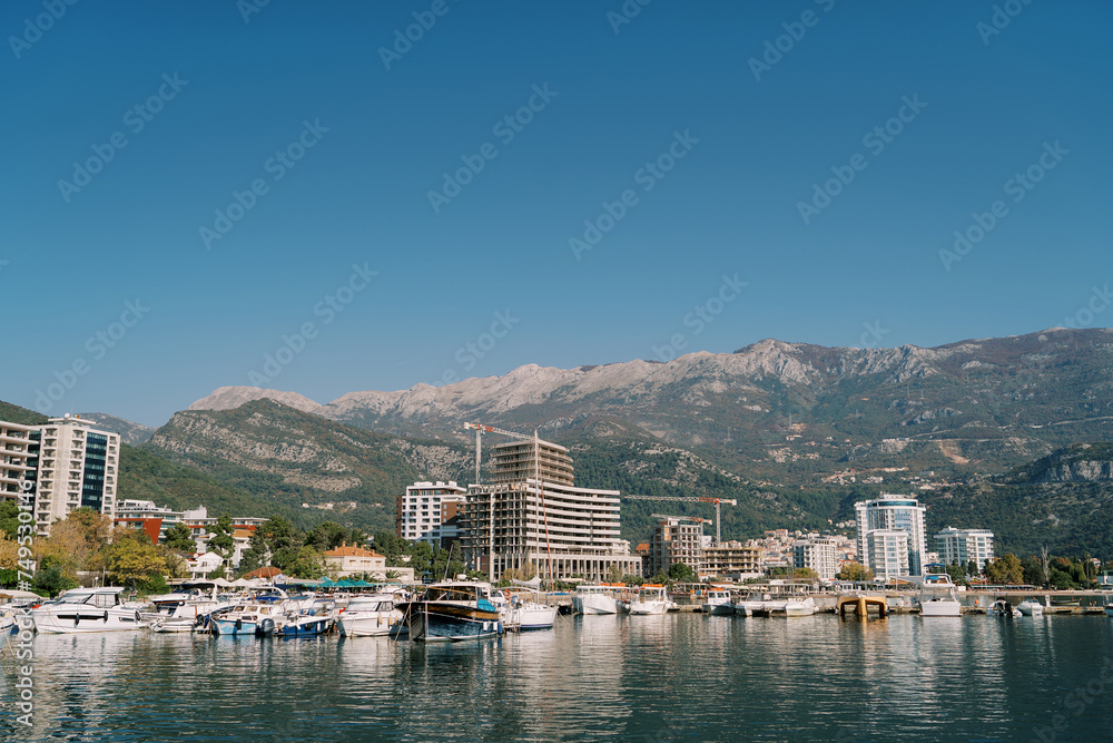 Motorboats along the shore of Budva and residential buildings under construction at the foot of the mountains. Montenegro