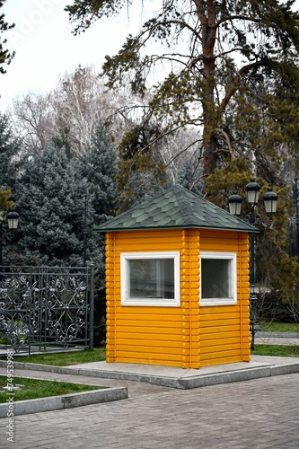 Yellow security guard booth with fir and pine trees in the background