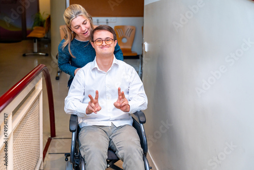 Health worker pushing a man with down syndrome using wheelchair photo