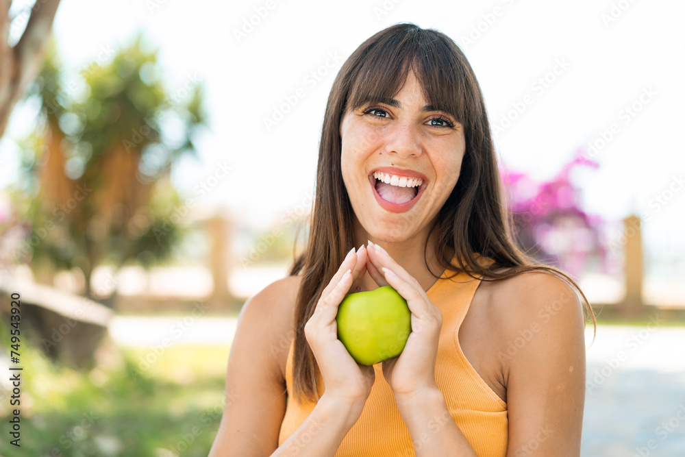 Young woman at outdoors holding an apple with surprised expression Young woman at outdoors holding an apple with surprised expression