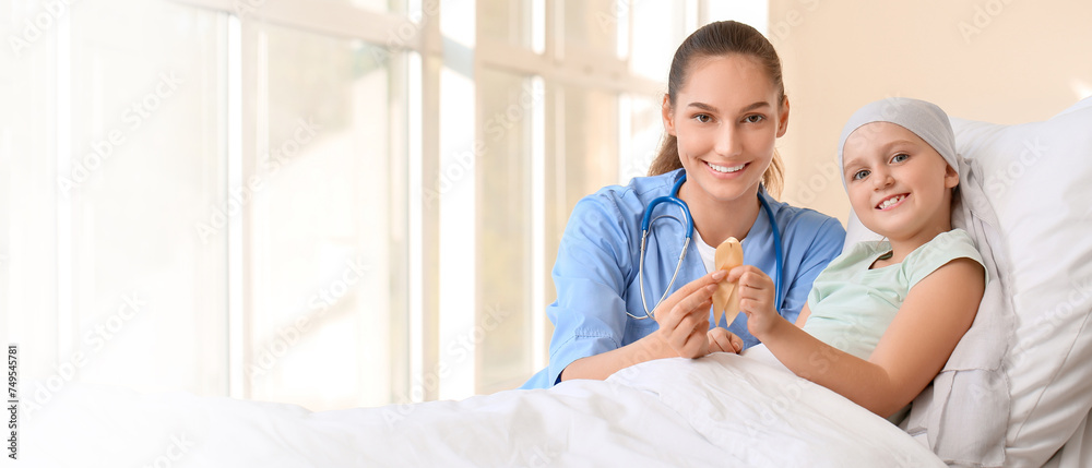 Nurse and little girl with golden ribbon in clinic. Childhood cancer awareness concept Nurse and little girl with golden ribbon in clinic. Childhood cancer awareness concept
