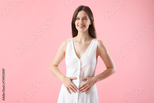 Young woman with healthy stomach on pink background