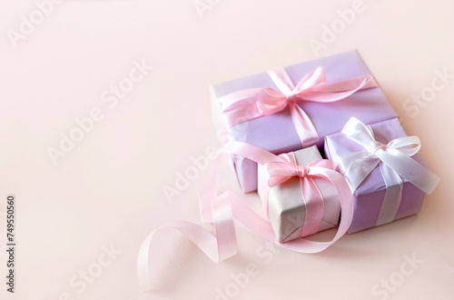 Present boxes on soft beige background. Gift boxes decorated with bowfemenine design. Holiday backdrop empty copy space. Women's day, mother's day.