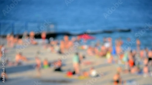 Many people relaxing on sandy beach of seashore and swimming in sea on hot sunny summer day. Many white-skinned people on sea public beach in summer. Rest vacation relax activity. Blurred background photo