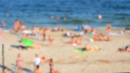 Many people relaxing on sandy beach of seashore and swimming in sea on hot sunny summer day. Many white-skinned people on sea public beach in summer. Rest vacation relax activity. Blurred background photo