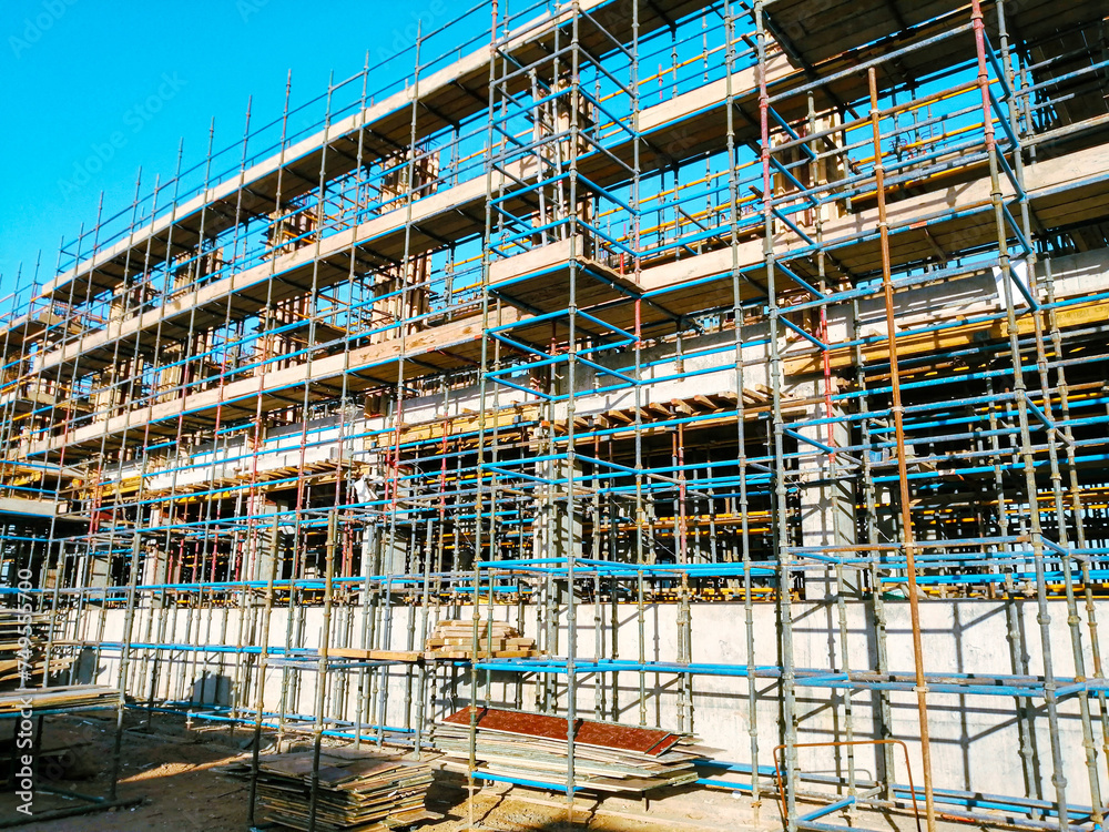 A building under construction with scaffolding and a blue ladder A building under construction with scaffolding and a blue ladder