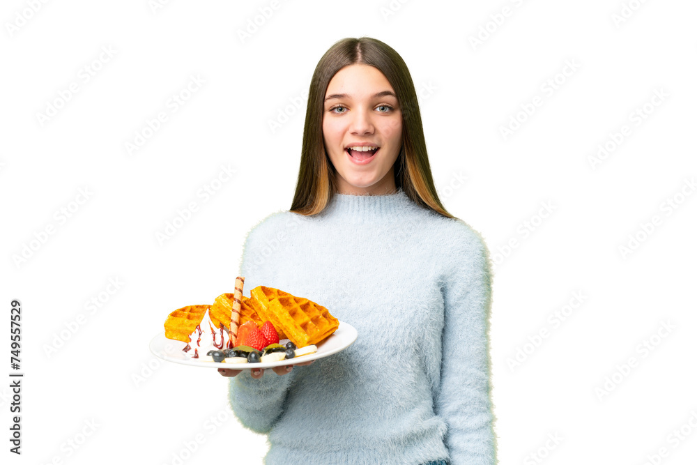 Teenager girl holding waffles over isolated chroma key background with surprise facial expression Teenager girl holding waffles over isolated chroma key background with surprise facial expression