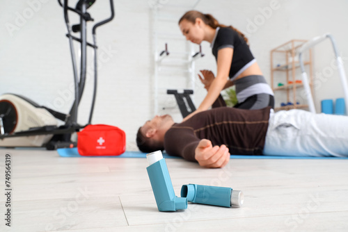 Asthma inhalers and trainer giving man first aid in gym, closeup